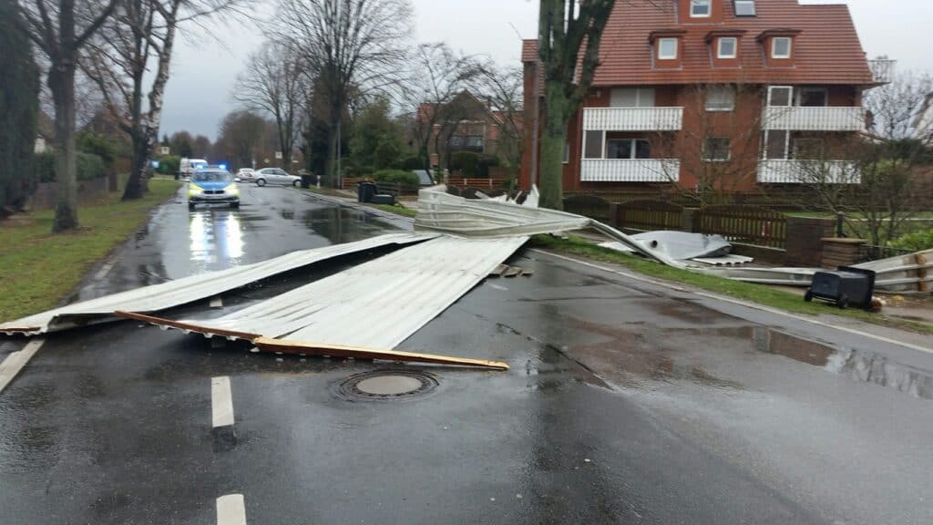 Sturmschaden blockiert Straße, Polizei vor Ort.