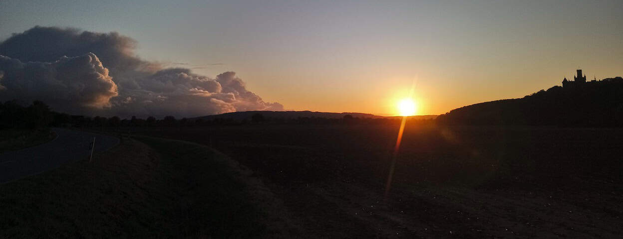 Sonnenuntergang über hügeliger Landschaft