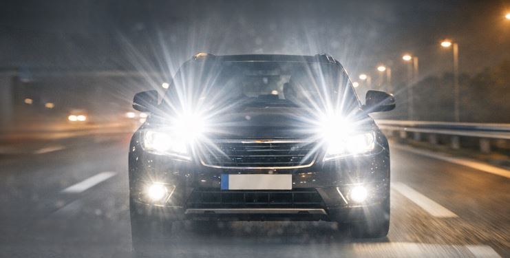 Auto mit eingeschaltetem Fernlicht auf nächtlicher Autobahn.