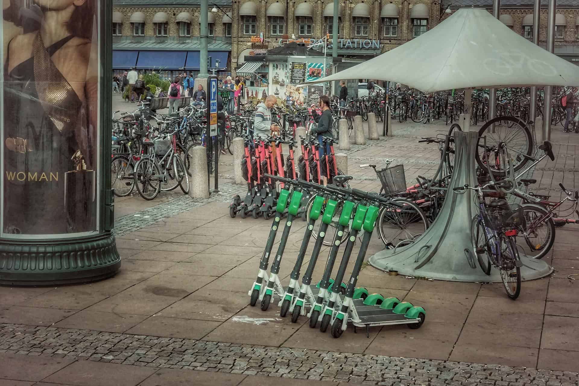 Leihroller und Fahrräder vor einem belebten Bahnhof